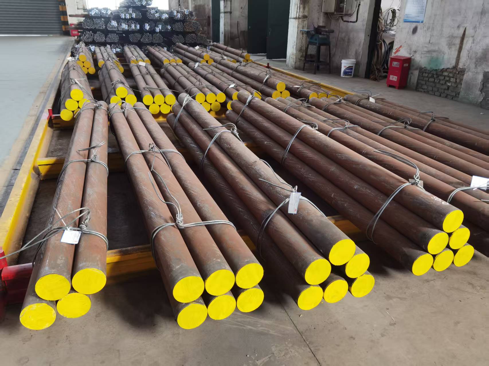 Bundled steel grinding rods with yellow-painted ends in a workshop