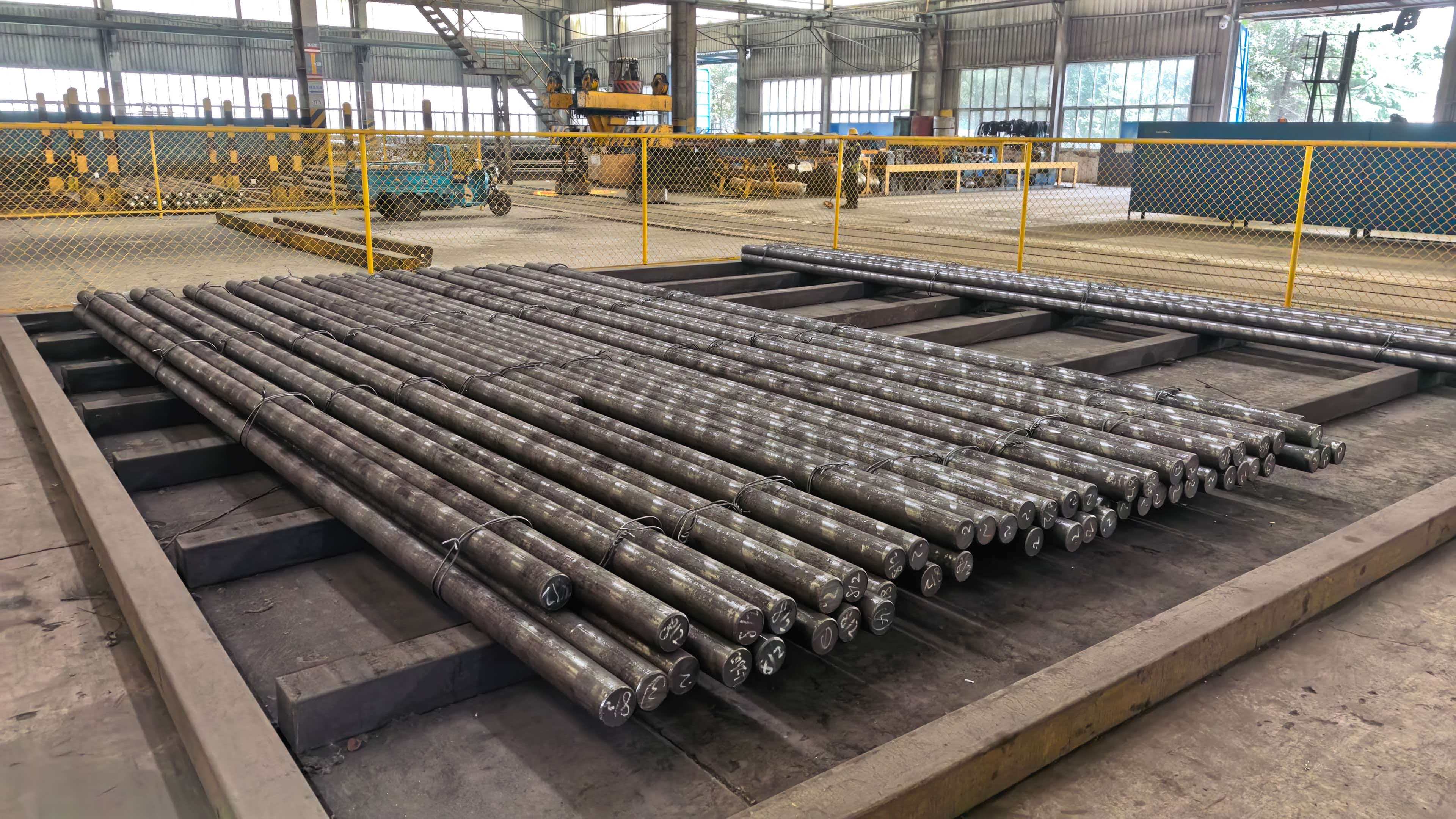Long round steel bars stored in parallel warehouse racks