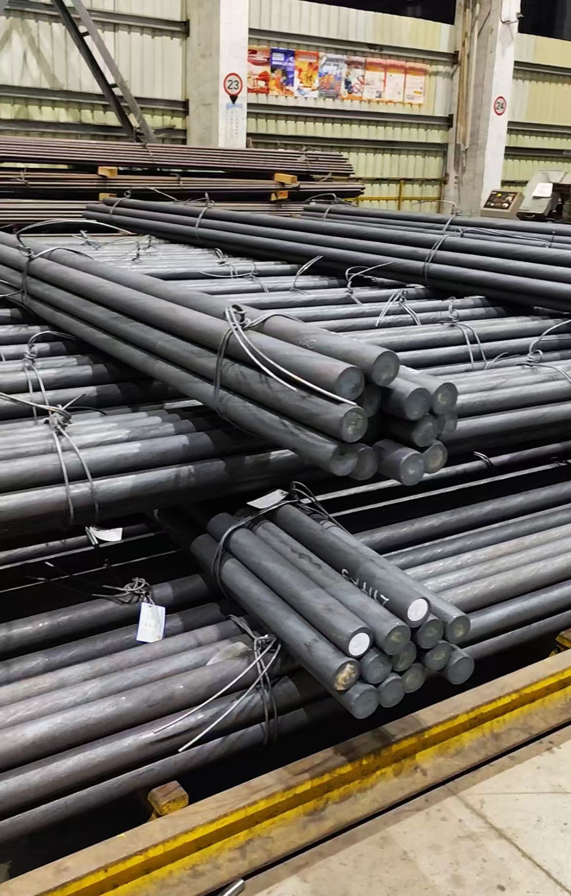 Bundles of long round steel bars staged inside an industrial warehouse