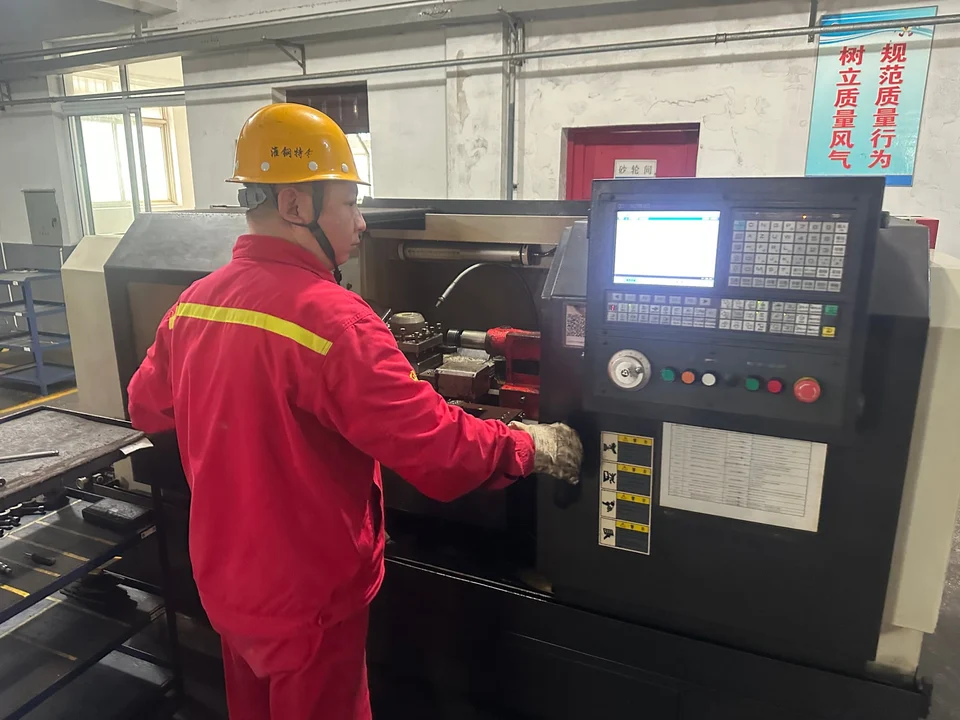 An operator preparing a metal test specimen on a lathe